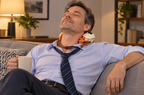 Man relaxing on the sofa with the massager on his neck